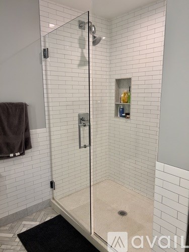 A bathroom with a walk in shower and a towel hanging on the wall.