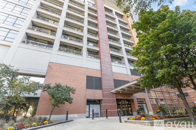 A tall building with a red brick entrance and balconies on the upper floors.