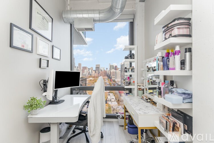 A white desk with a computer and a chair in front of a window with a city view.