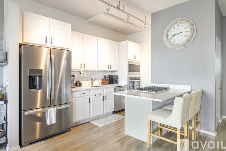 A modern kitchen with a stainless steel refrigerator and white cabinets.