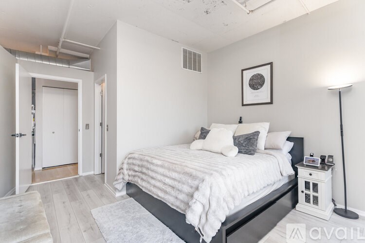 A bedroom with a bed, nightstand, and lamp.