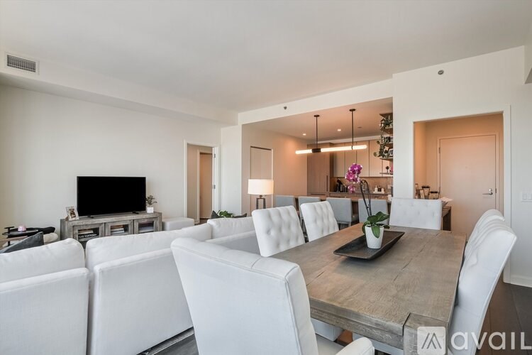 A modern living room with a white sofa set and a wooden dining table.