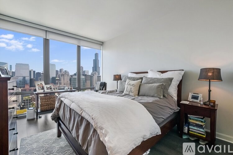 A bedroom with a large bed and a city view through the window.