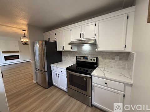 A kitchen with white cabinets and a stainless steel refrigerator.