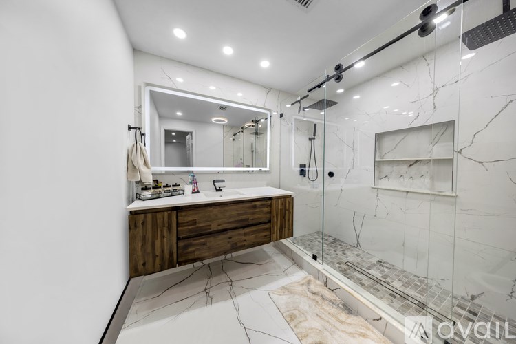A modern bathroom with a marble floor and a large mirror above the sink.