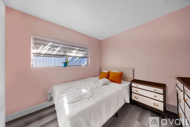 A bedroom with a bed, nightstand, and window with blinds.