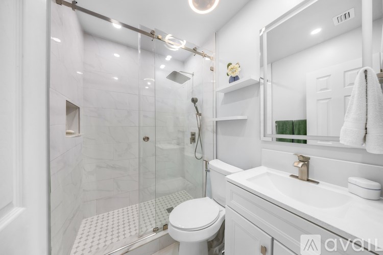 A white bathroom with a toilet, sink, and shower.