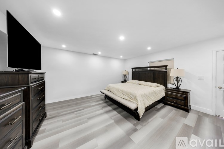 A bedroom with a large bed, a dresser, and a flat-screen TV.