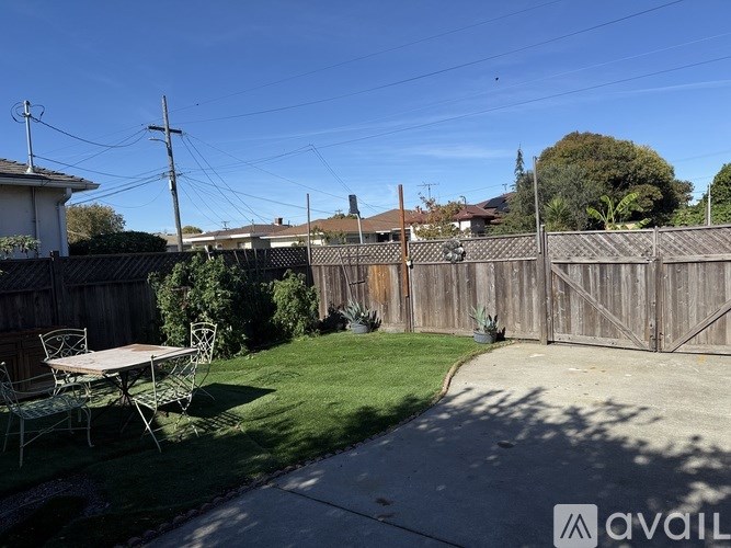 A backyard with a wooden fence and a picnic table.