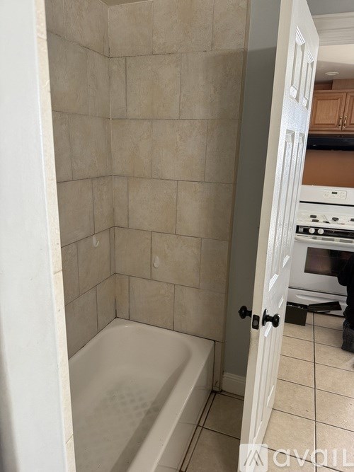 A bathroom with a tub and a doorway leading to a kitchen.