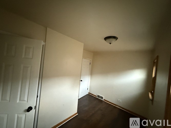 A room with a white door and a brown floor.