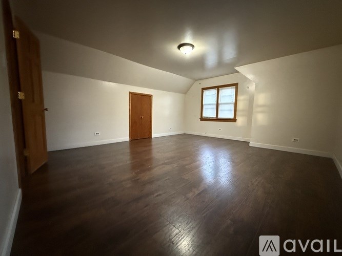 A room with wooden floors and a window on the right side.