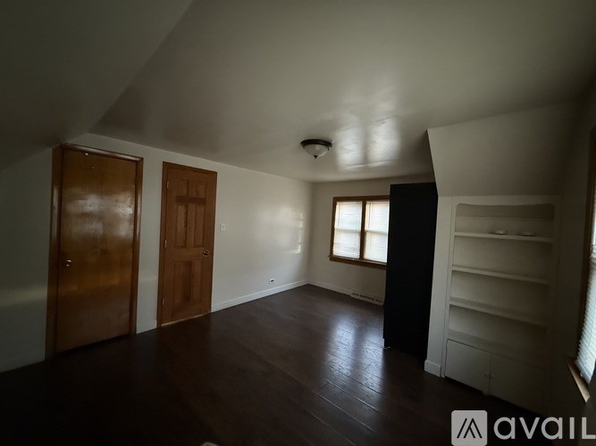 A room with wooden floors and white walls, with a window on the right side.