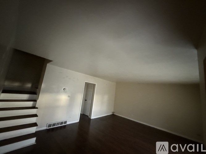 A room with a staircase on the left and a door on the right.