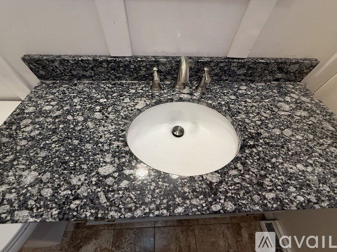 A bathroom sink with a granite countertop and a white basin.