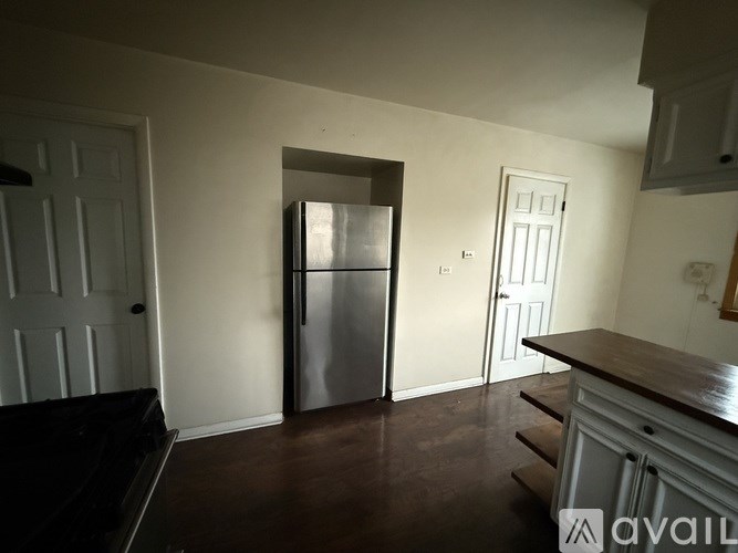 A kitchen with a refrigerator, sink, and cabinets.