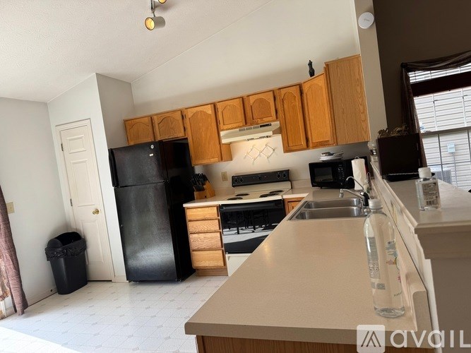 A kitchen with wooden cabinets and a black fridge.