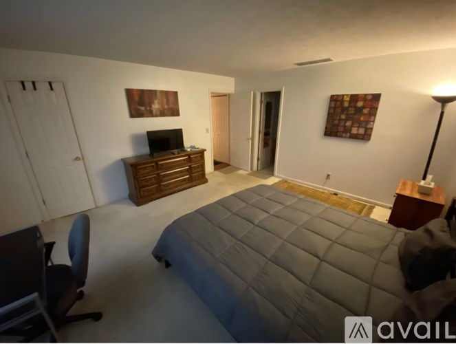 A bedroom with a large bed, a chair, and a television.