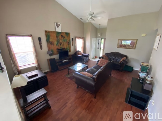 A living room with a brown leather couch and a painting on the wall.