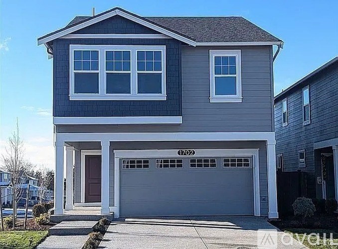 A two-story house with a garage and a driveway.