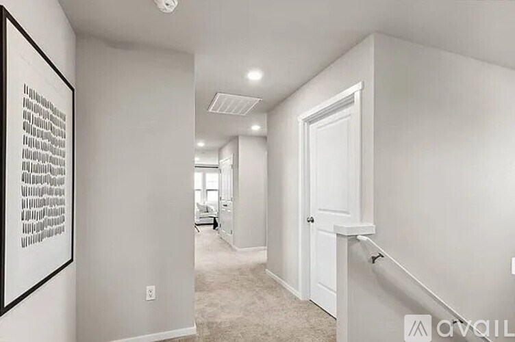 A hallway with a white door and a framed picture on the wall.