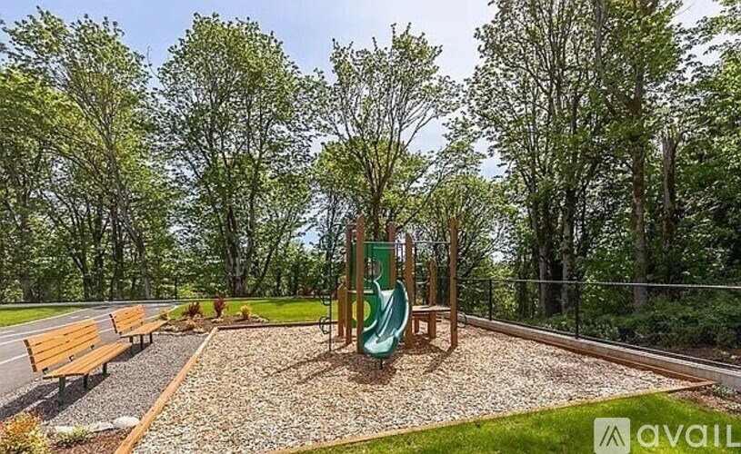 A playground with a green slide and wooden benches.