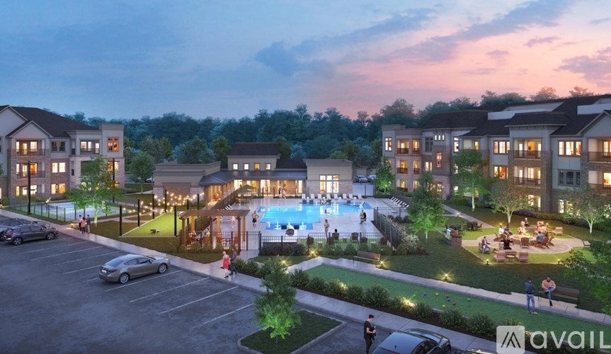 A modern apartment complex with a pool and a lit-up parking lot.