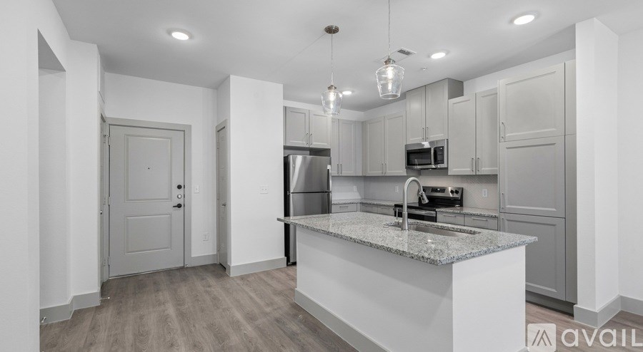 A kitchen with a granite countertop and stainless steel appliances is available for rent.