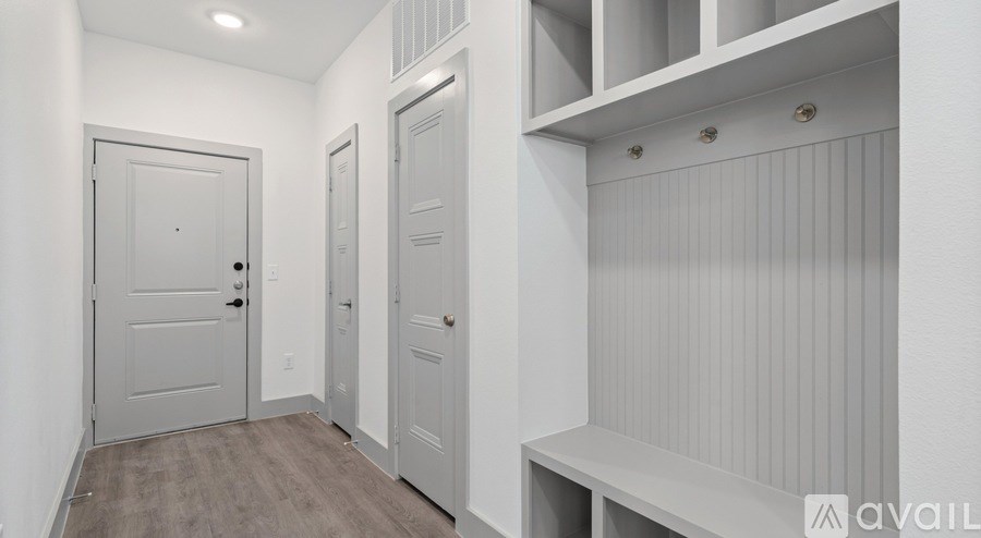 A white hallway with a bench and three doors.