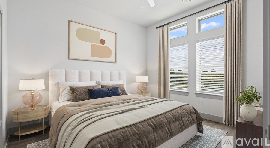 A bedroom with a large bed, two lamps, and a framed picture on the wall.