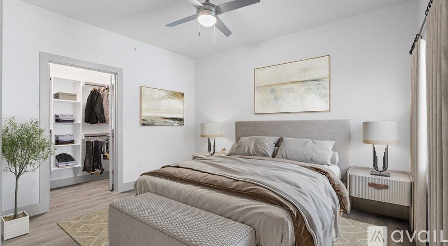 A bedroom with a large bed, a ceiling fan, and a painting on the wall.