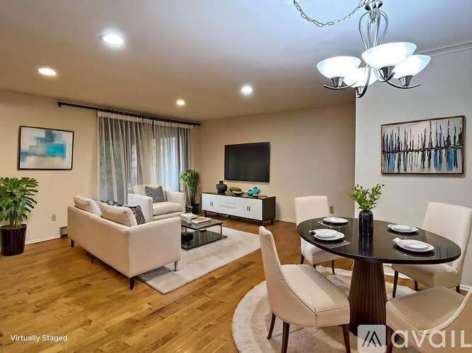 A living room with a white sofa, a black coffee table, and a TV on the wall.