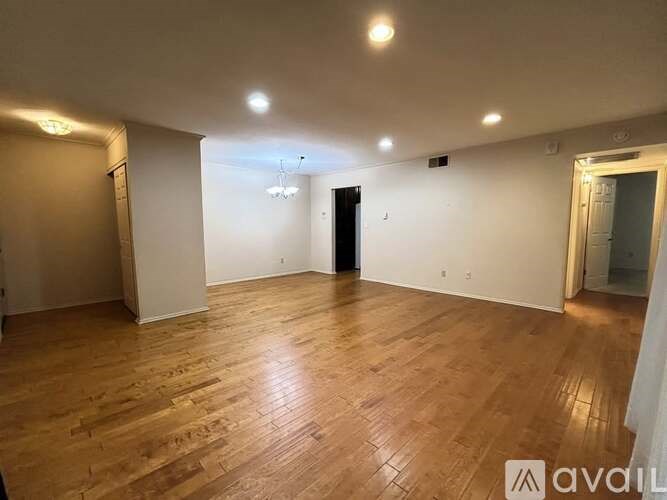 A spacious room with wooden flooring and white walls.