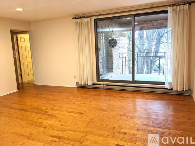A room with wooden flooring and a sliding glass door leading outside.