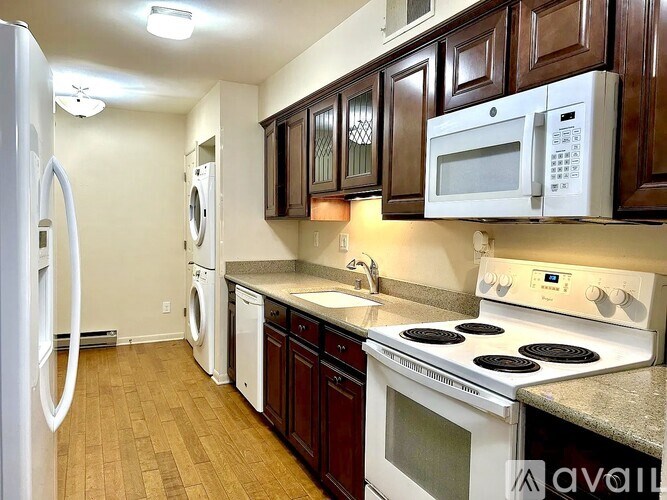 A kitchen with white appliances and brown cabinets.