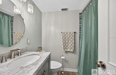 A bathroom with a marble countertop and a round mirror.