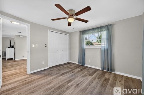 A room with a ceiling fan and wooden flooring.