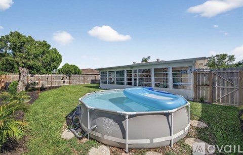 A round above ground pool with a blue cover sits in a backyard.