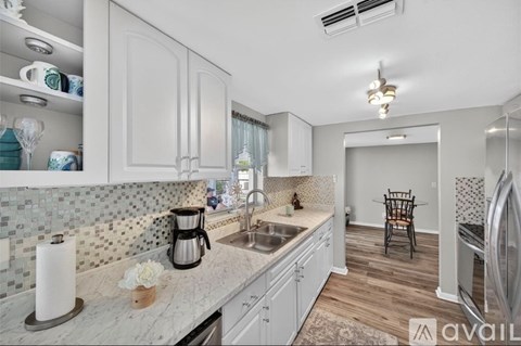 A kitchen with white cabinets and a marble countertop.