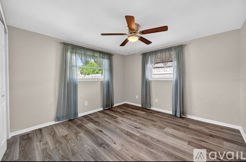 A room with a ceiling fan and wooden flooring.