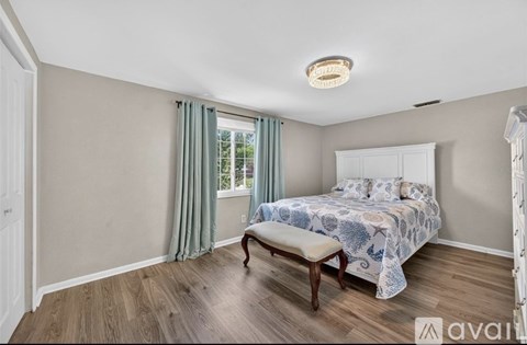 A bedroom with a bed, bench, and window.