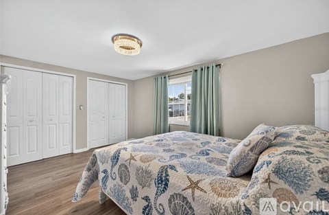 A bedroom with a bed covered in a blue and white patterned bedspread.