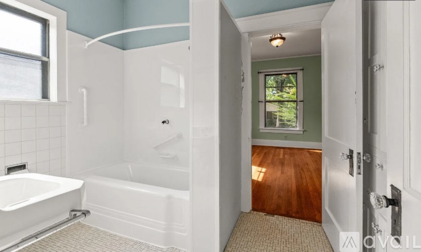 A bathroom with a white tub and a window.
