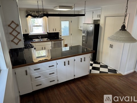 A kitchen with white cabinets and a black and white checkered floor.