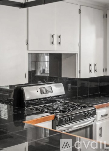 A modern kitchen with a stove top oven and white cabinets.