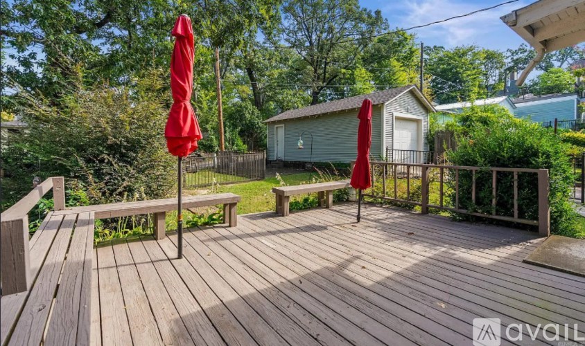 A wooden deck with a bench and two red umbrellas.