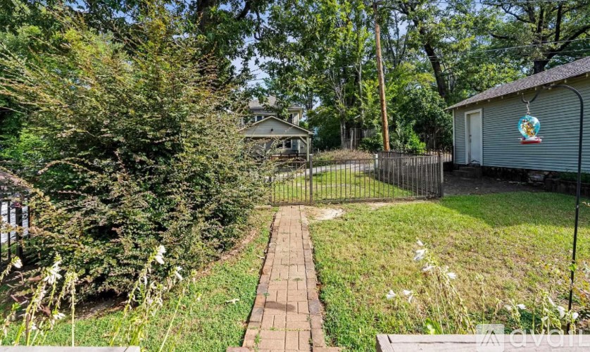 A backyard with a brick walkway leading to a house.