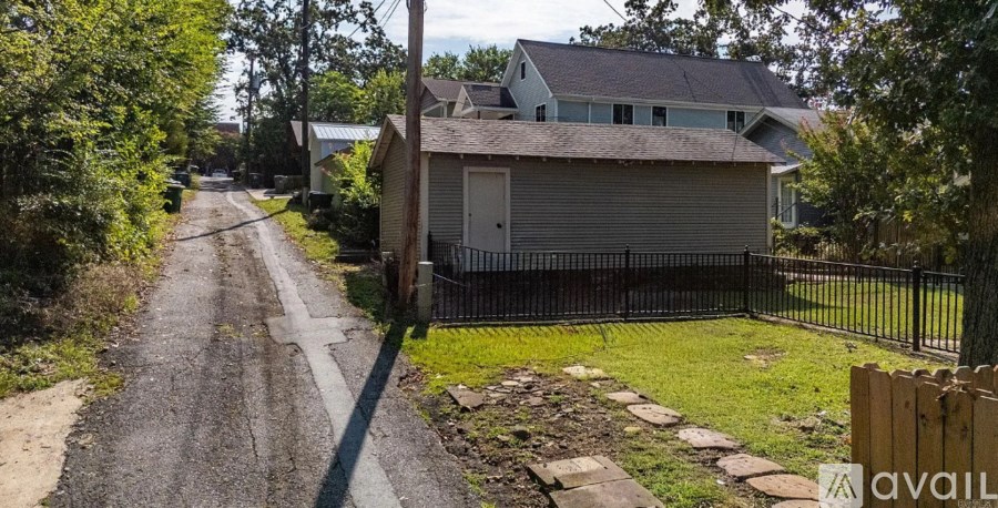 A residential street with houses on both sides and a dirt road.