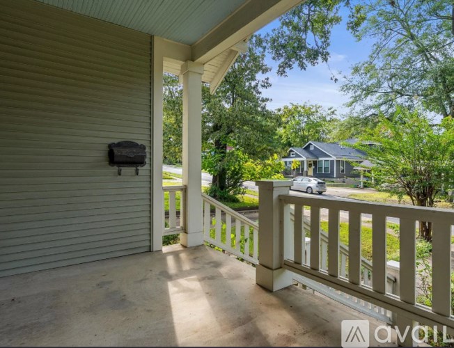 A porch with a white railing and a mailbox on the wall.