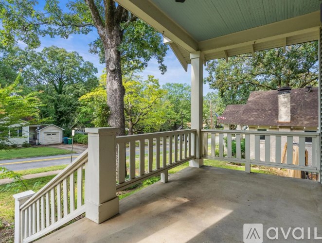 A porch with a white railing and a tree in the background.